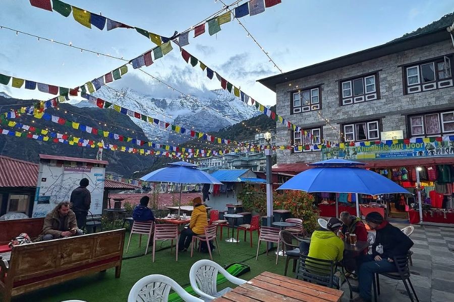 Namche Bazaar outdoor cafe with prayer flags and mountain backdrop